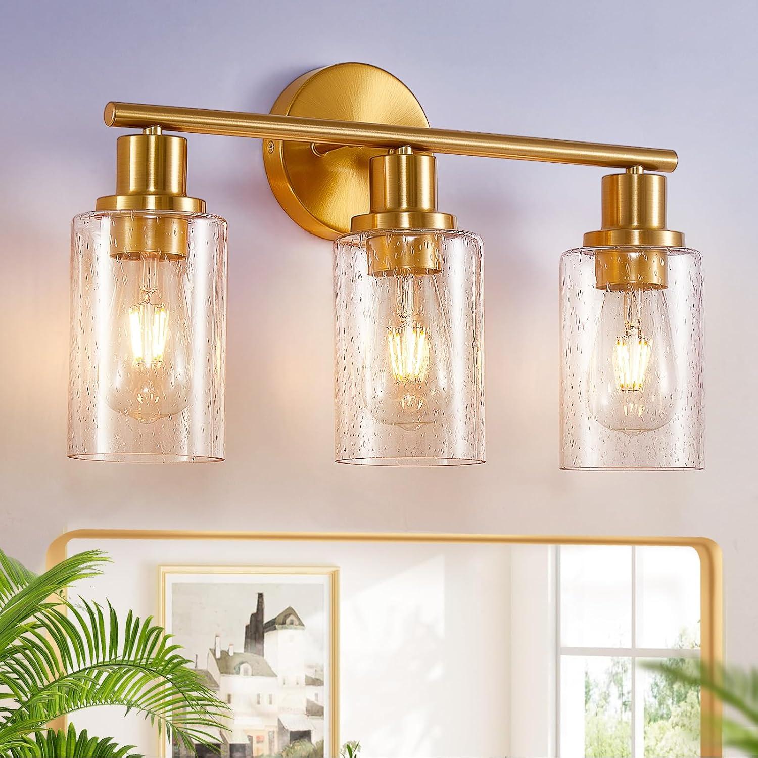 Gold bathroom vanity light with bubbled glass shades glowing above a mirror, styled with plants and warm neutral bathroom decor.