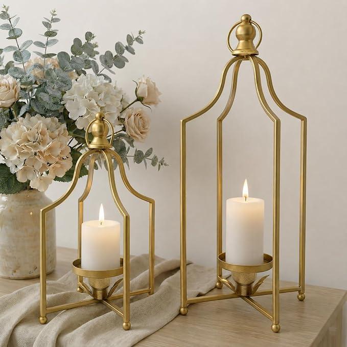 Antique gold decorative lanterns with white pillar candles on a rustic wood surface